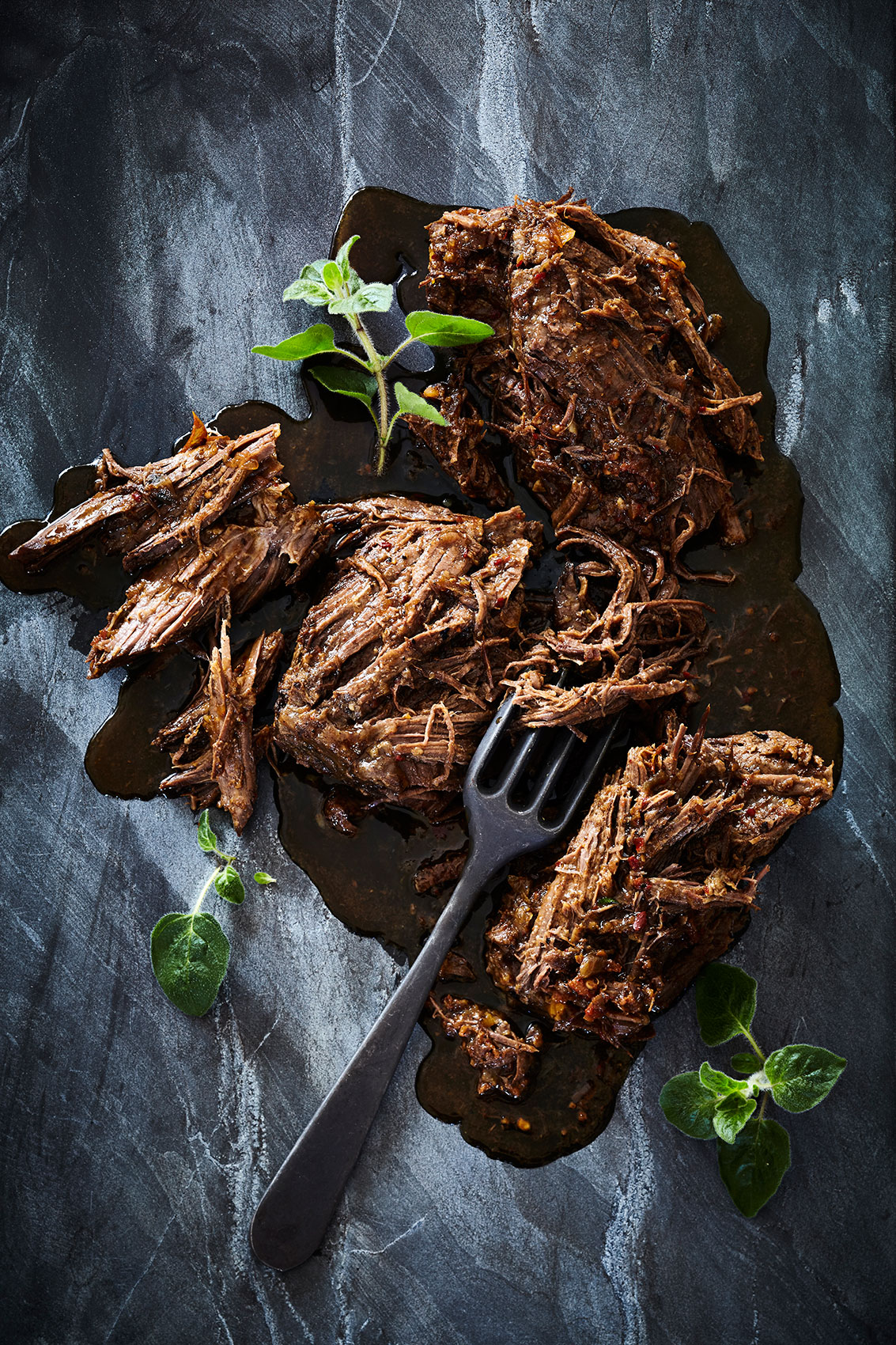 Slow Cooked • Pulled Beef with Black Fork on Textured Stone Bench • Cookbook & Editorial Food Photography