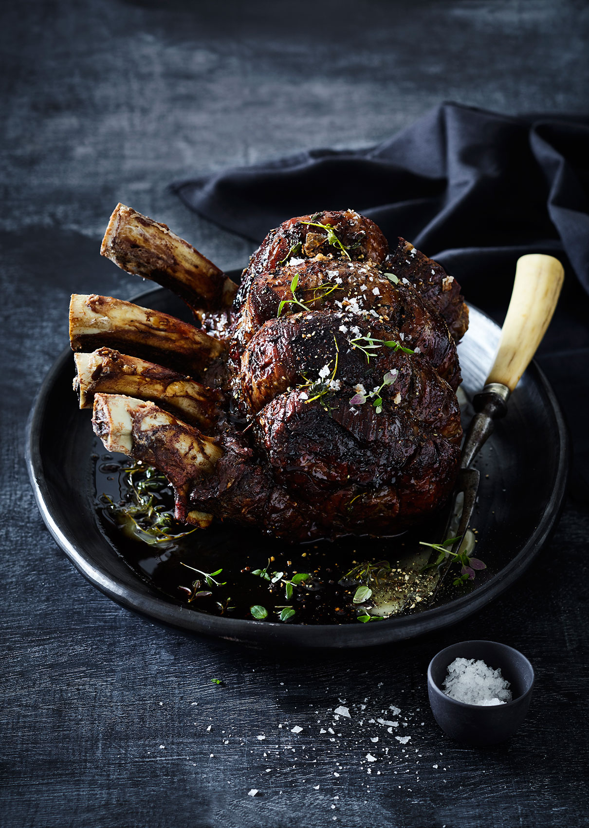 Slow Cooked • Standing Roast with Fresh Herbs & Rock Salt in Dark Dish • Cookbook & Editorial Food Photography