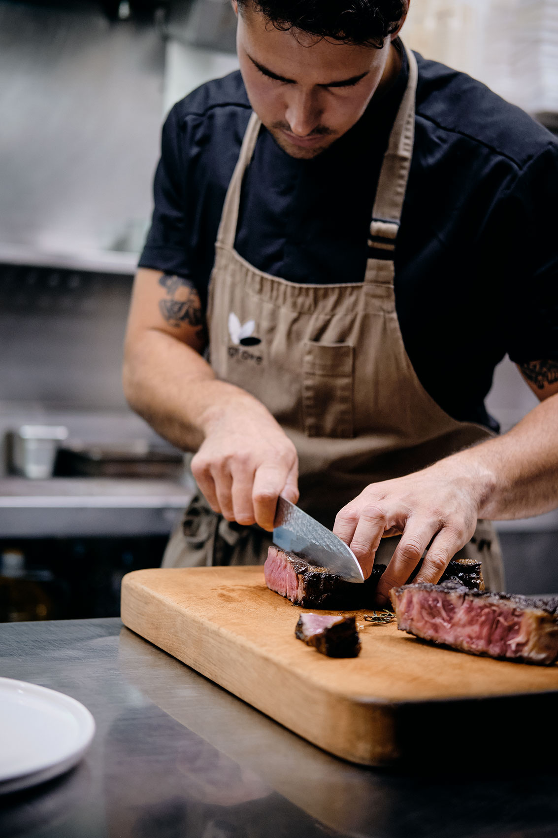 The Grove Cutting & Plating Steak on Wooden Board • Hospitality & Culinary Food Photography